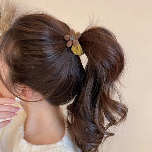 Détail de l'élastique à cheveux fleur floquée avec strass sur queue de cheval haute