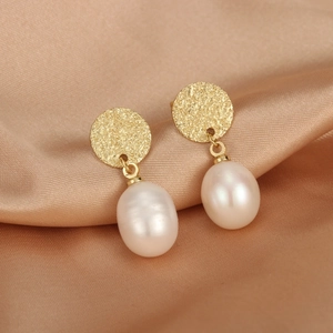 Close-up of gold hammered metal stud earrings with elegant white teardrop pearls