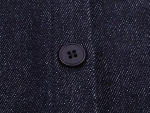 Macro view of dark blue denim fabric texture with a black four-hole resin button detail