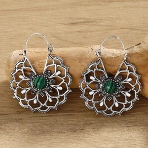 Detailed macro of vintage silver flower earrings featuring turquoise stones on wood
