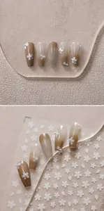 Detail of long coffin nails with brown gradient, 3D cherry blossoms and pearl accents