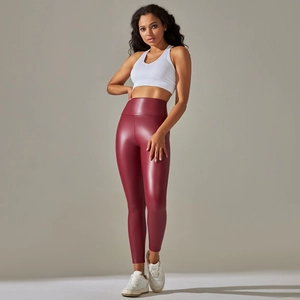 Detail of high waisted burgundy faux leather leggings with a glossy PU finish and slim fit