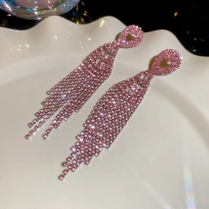 Macro detail of sparkling pink rhinestone tassel earrings on a decorative shell plate