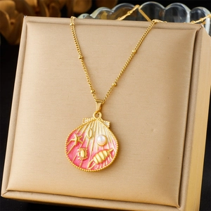 Detailed close-up of shell pendant with pink enamel, pearl, and starfish on gold necklace