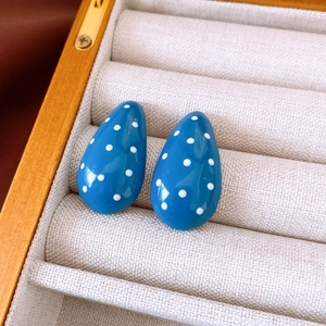 Detail of blue teardrop resin earrings with white polka dots in a beige velvet gift box