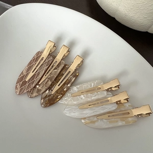Acetate hair clips set with marble and tortoiseshell patterns on a white plate