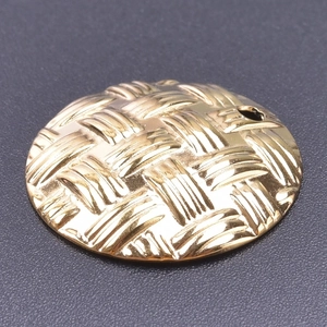 Detail of a round 18k gold plated stainless steel pendant with a woven texture