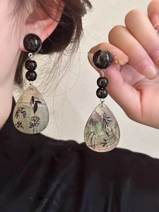 Detail of tear-drop shell earring with black ink bamboo and floral patterns