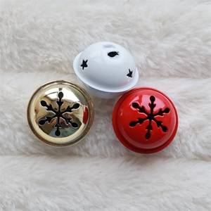Close-up of gold, red, and white Christmas bells with snowflake and star hollow designs