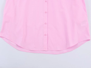 Detail of light pink poplin shirt showing buttons and curved hem on white background
