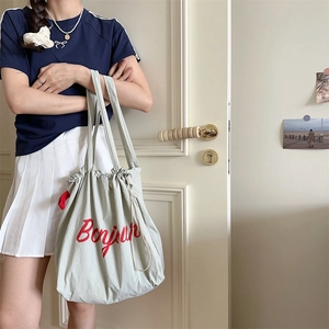 Detail of light grey drawstring tote bag with red Bonjour text print on nylon