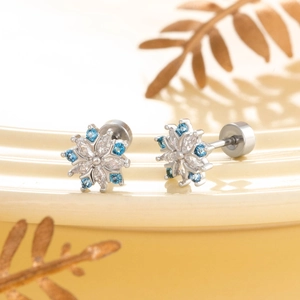 Silver snowflake earrings with blue and white cubic zirconia on a ceramic plate