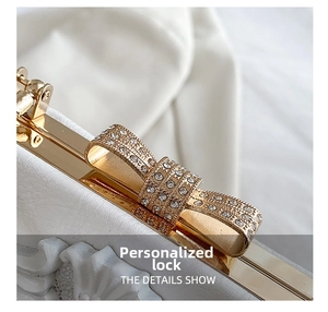 Close-up of golden bow-shaped clasp with sparkling rhinestones on elegant white handbag