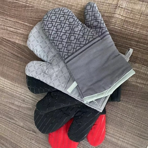 Stack of grey, black and red heat-resistant oven mitts with non-slip texture on wood