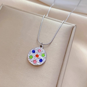 Macro detail of hammered silver disc pendant with colorful zircon stones on snake chain
