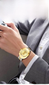 Detail shot of a luxury gold quartz watch with diamond dial on a male wrist in a grey suit