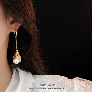 Élégantes boucles d'oreilles pampilles en perles dorées portées par un mannequin