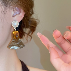 Detail of elegant fan-shaped resin earrings with pearls on model's ear