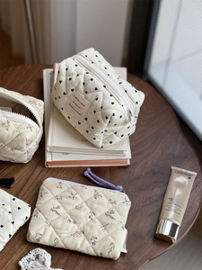 Quilted corduroy makeup bag with heart prints and floral pouch on a wooden table