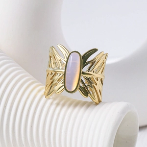Elegant gold oval moonstone ring featuring hollow butterfly wing textures on white pedestal