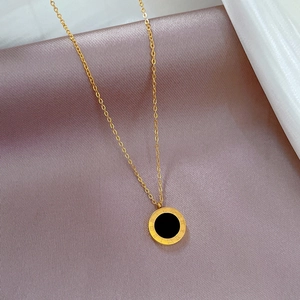 Dettaglio della collana con pendente a numeri romani d'oro su tessuto di raso viola