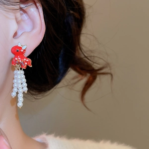 Close-up of red enamel kylin earrings with white pearl tassels worn by a model