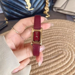 Detailed close-up of a vintage square gold watch with red dial and red leather strap