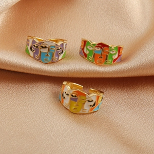 Artistic gold-plated drip oil open rings with abstract face designs on gold silk cloth