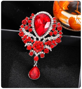 Macro view of crystal teardrop brooch with red ruby-style stones on black velvet
