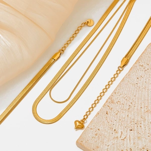 Detailed macro view of triple-layered golden stainless steel snake chain and heart charm