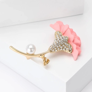 Detail of gold floral brooch featuring pink petals, white pearl and sparkling crystals