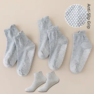 Detail showing non-slip white silicone grippers on the bottom of grey knit baby socks
