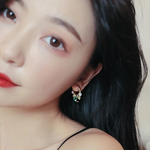 Detailed shot of gold tassel earrings with green and white crystals on model