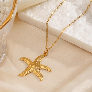 Golden starfish pendant necklace on white textured stone with elegant silk background