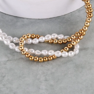 Detail of baroque pearl and gold bead necklace on a textured stone display