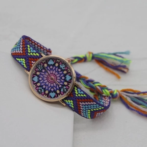 Detail of bohemian woven rope strap and gold mandala pattern dial on quartz watch