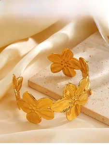 Dettaglio del bracciale rigido floreale dorato con finitura opaca su fondo di raso