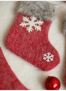 Detail of red Christmas stocking with grey faux fur cuff and white snowflake appliqué
