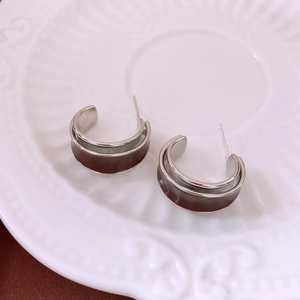 Close-up of vintage C-shape dark red enamel earrings on a white ceramic plate