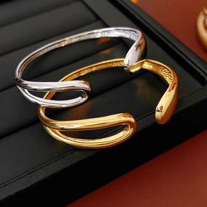 Detailed view of gold and silver teardrop open bangles on a jewelry tray