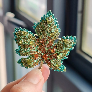 Close-up of maple leaf brooch featuring vibrant gradient crystals and gold-tone finish