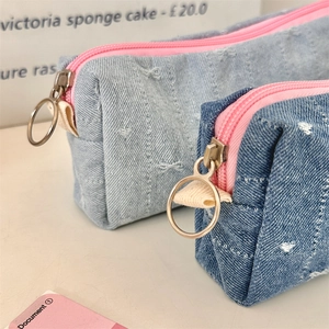 Close-up of denim pencil case with heart embroidery, pink zipper and metal ring puller