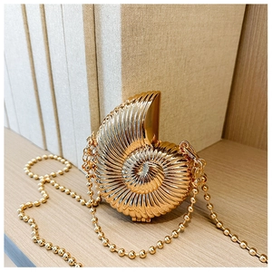 Detailed view of metallic gold conch mini bag with spiral texture and beaded chain