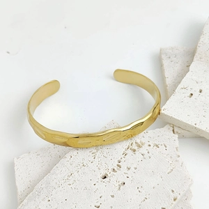 Minimalist golden stainless steel open cuff bracelet featuring a textured hammered finish