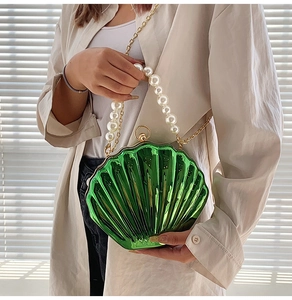 Detailed view of emerald green shell bag with pearl handle and golden chain strap
