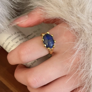Detailed shot of vintage gold ring with oval lapis lazuli stone on hand with fur cuff