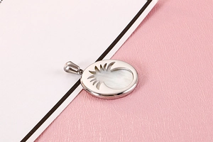 Detailed close-up of oval silver pendant featuring white shell inlay and pineapple cutout