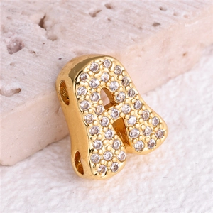 Macro shot of gold letter A pendant with white zircon inlay on stone surface