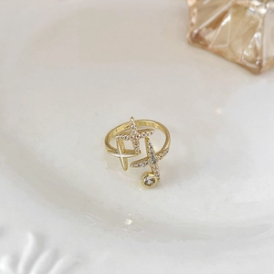 Dettaglio dell'anello a stella placcato oro con zirconi su un piatto bianco texturizzato