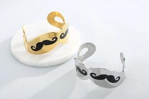 Detail of gold and silver mustache-shaped open bracelets on a stone display